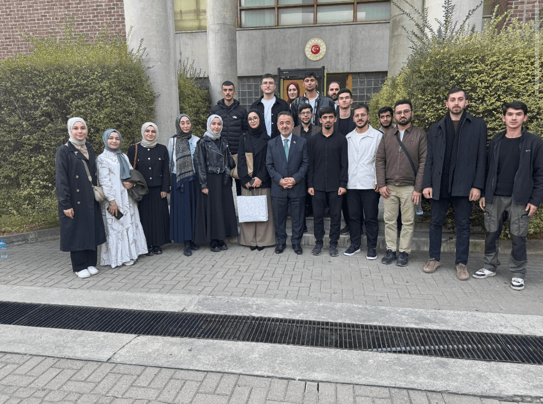 Öğrenciler ve bir takım elbiseli katılımcının bina önündeki toplu fotoğrafı